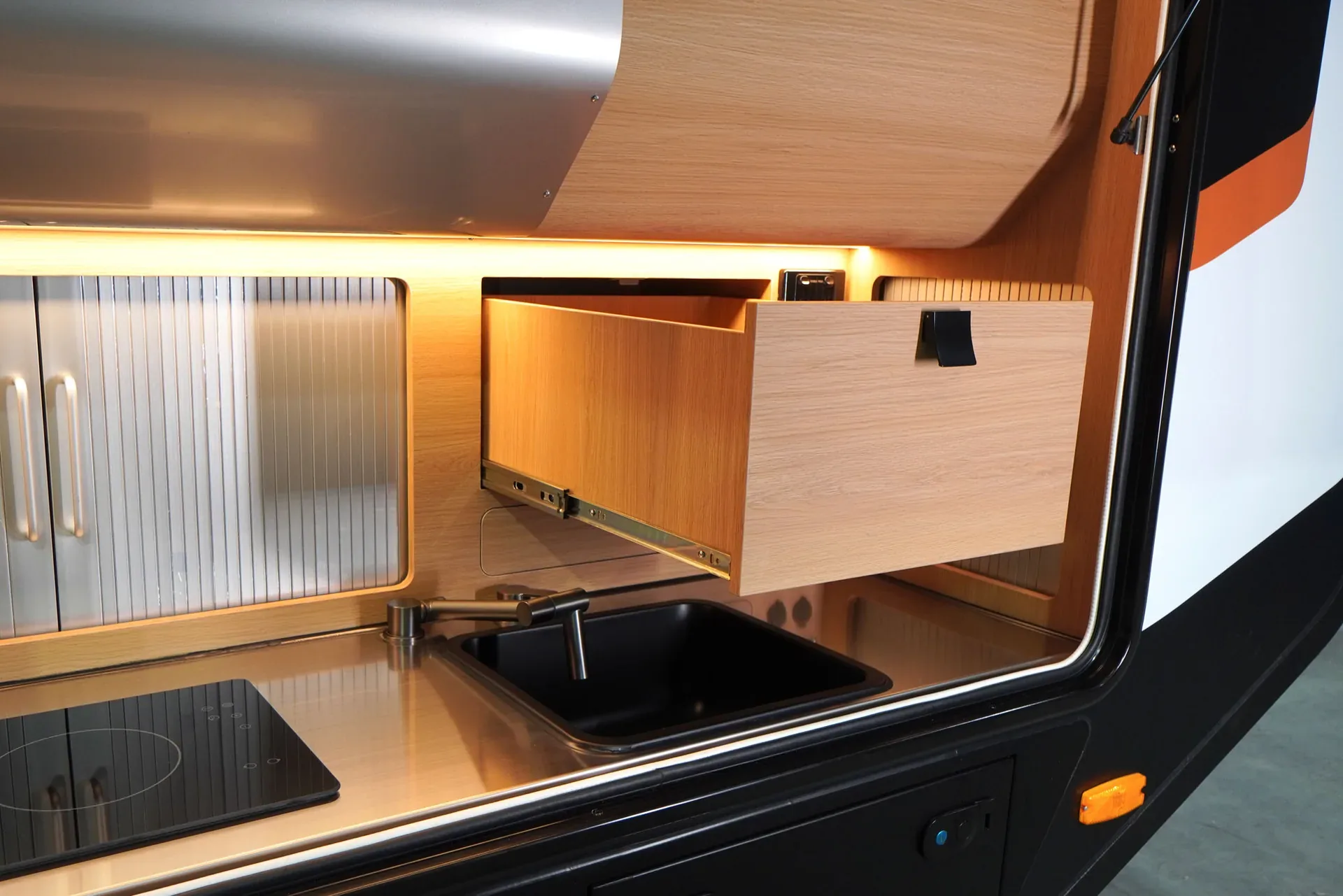 Trekka external kitchen cupboard open beside the cooktop and sink