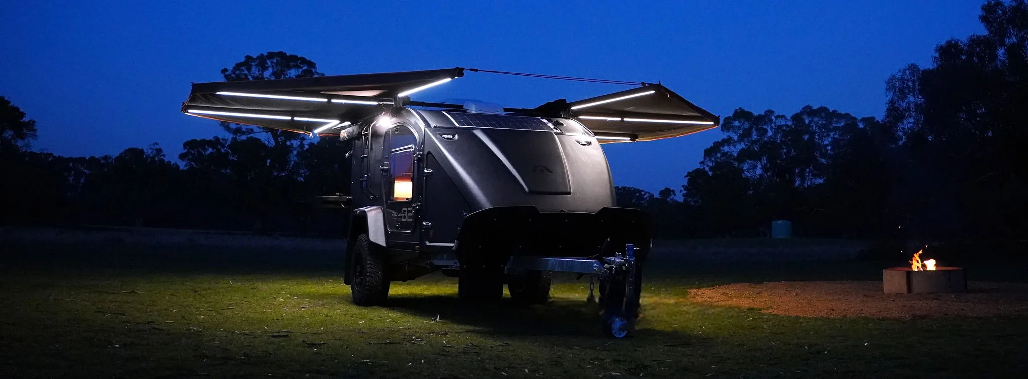 Rover 02 set up at dusk with both 180 awnings extended and their LED lights on