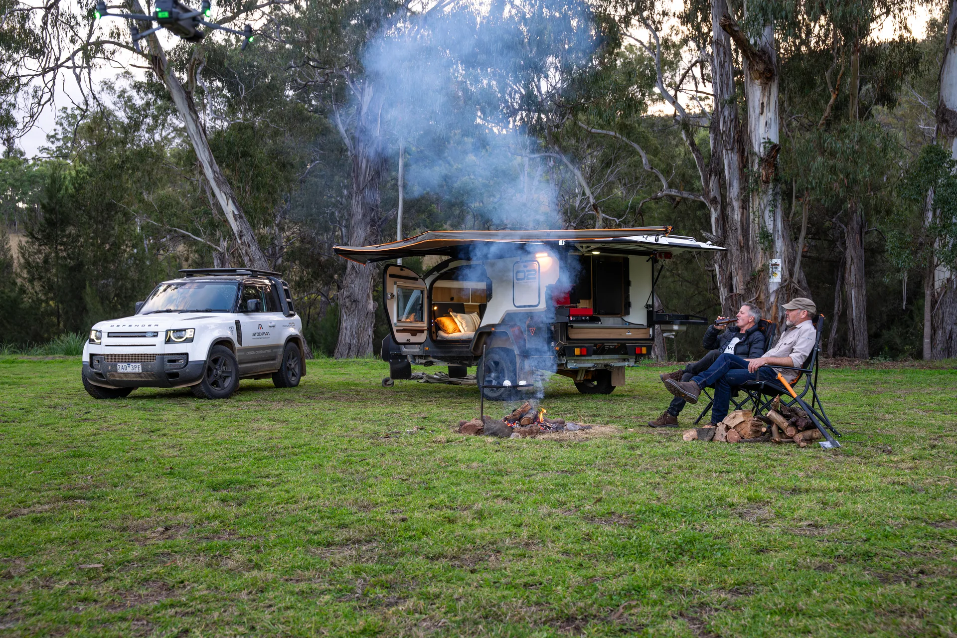 Two Stockman owners relaxing by the campfire beside their Rover 02 at a bush camp
